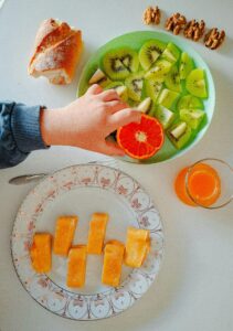 Top view of a healthy breakfast setup with fresh fruits, nuts, and juice on a table.